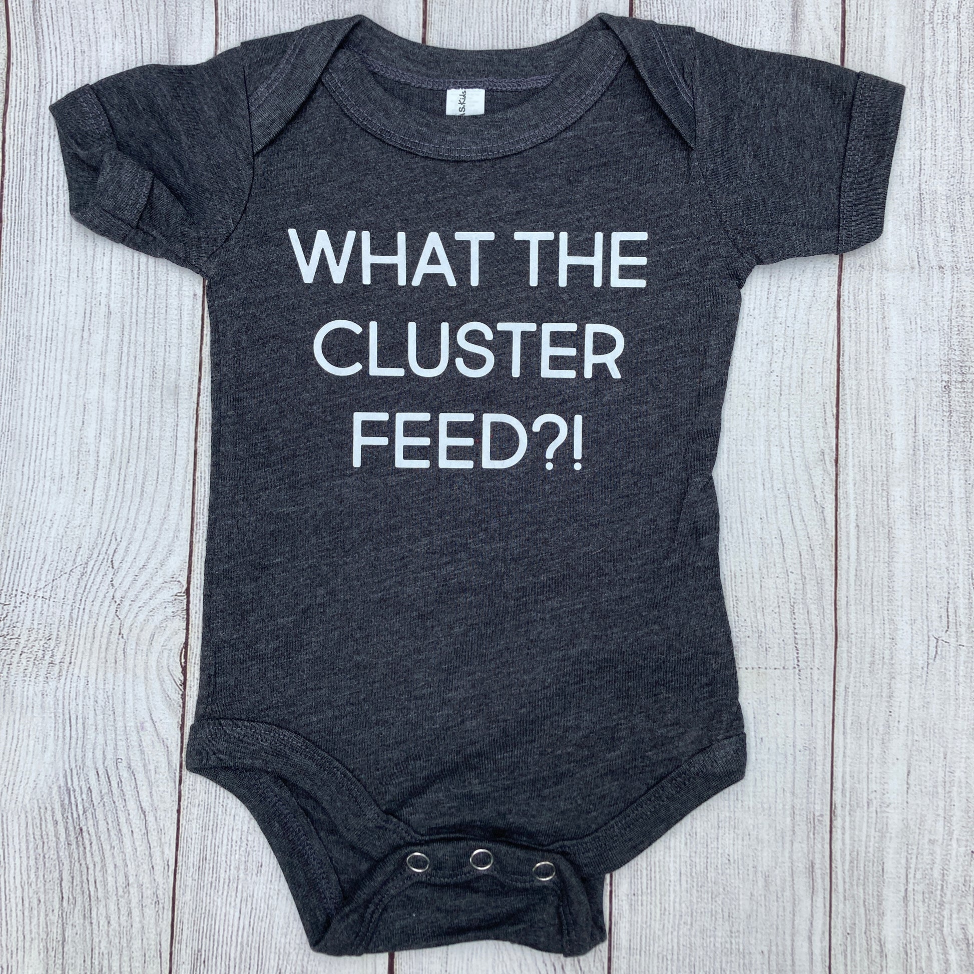 Grey baby bodysuit, "What the cluster feed?!" in white letters, baby, onesie, bodysuit, newborn, cluster feed, bf, breastfeeding, fed is best, breastfeeding mama, growth spurt, motherhood, new mom, nursing, pumping mom, colic