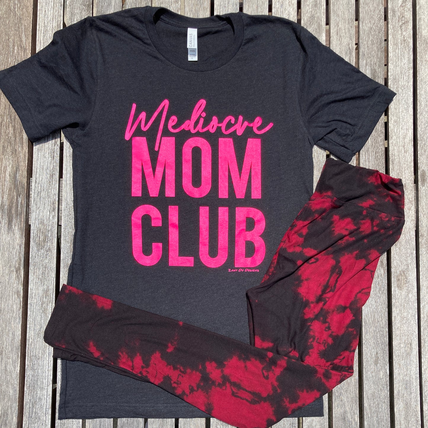 Mom club neon pink on black stacked tee with the writing in neon pink saying, "Mediocre MOM CLUB"