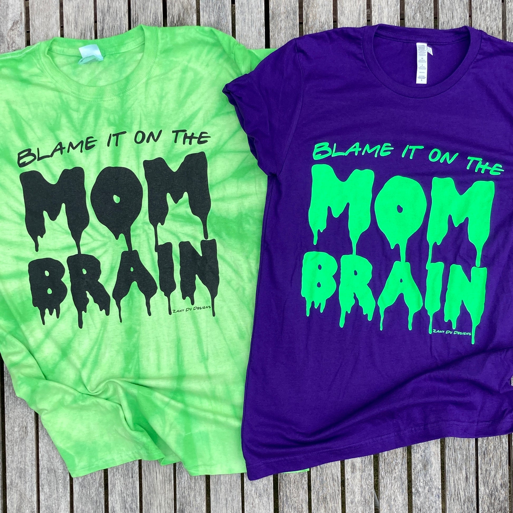 Slime purple and neon green tee with the writing saying, "BLAME IT ON THE MOM BRAIN" and the MOM BRAIN part has a slime font - Brain - Spooky - Halloween