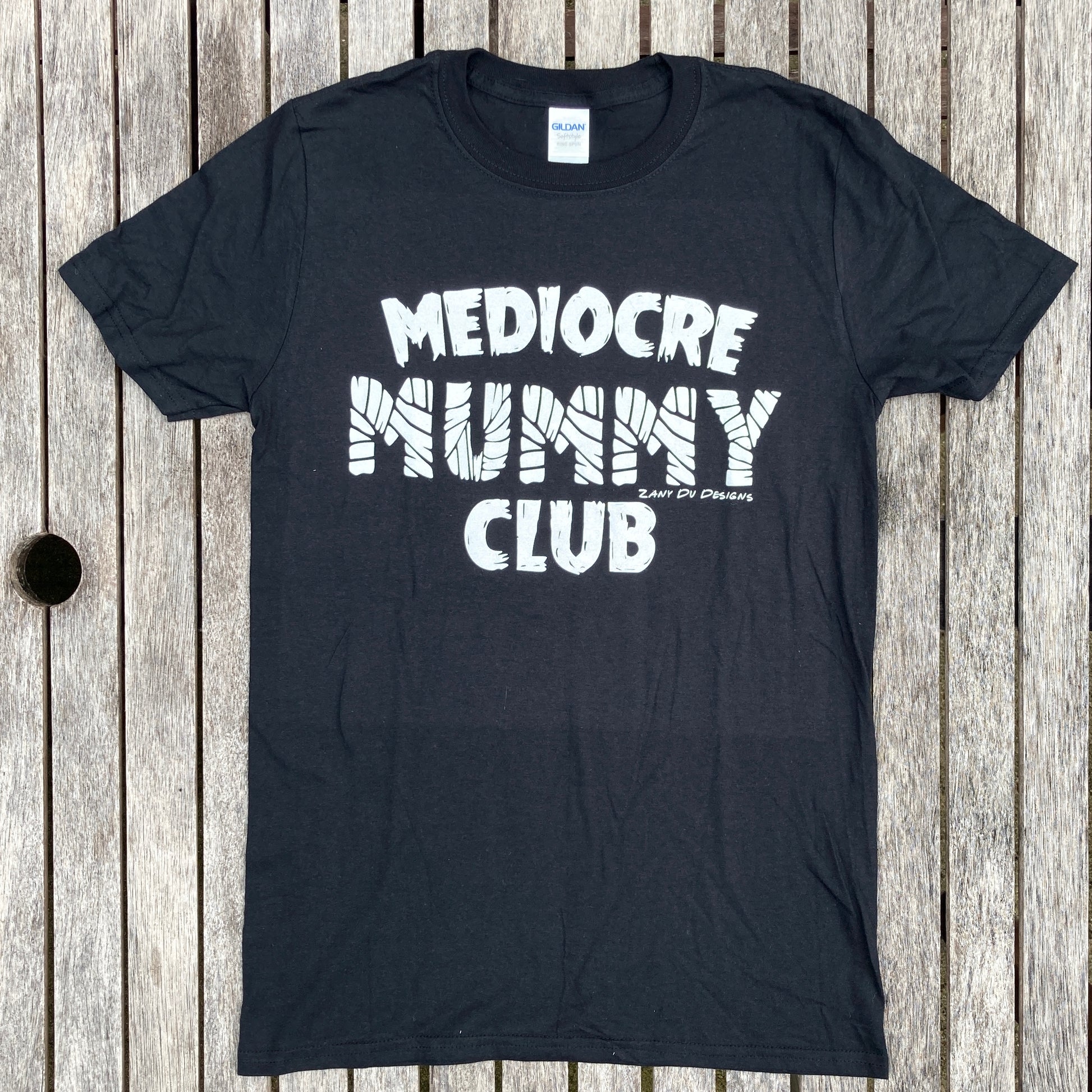 Black mummy club tee shirt with the writing saying, "MEDIOCRE MUMMY CLUB" 'Mummy' in a mummy wrapped font.
