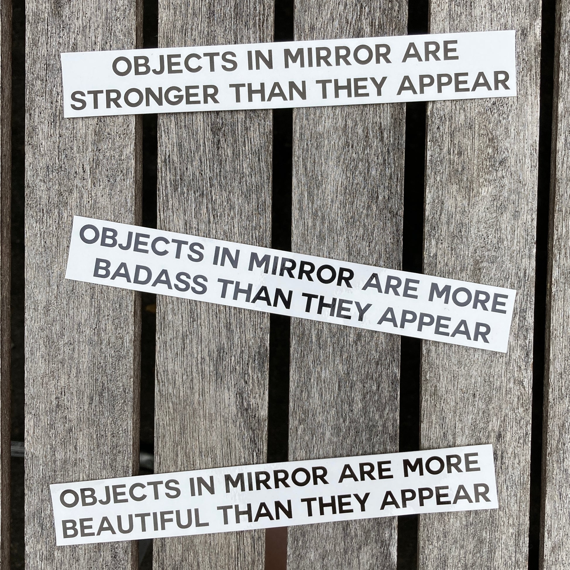 3 affrimation stickers that say, "objects in mirror are stronger than they appear", "objects in mirror are more badass than they appear", and "objects in mirror are more beautiful than they appear"