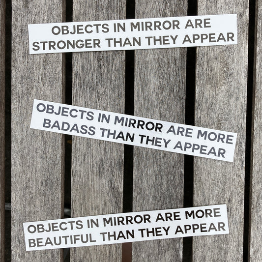 3 affrimation stickers that say, "objects in mirror are stronger than they appear", "objects in mirror are more badass than they appear", and "objects in mirror are more beautiful than they appear"