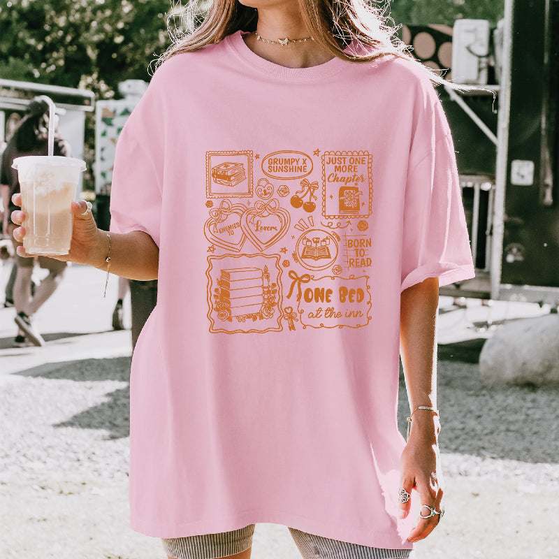 Person wearing a pink t-shirt with graphic designs outdoors