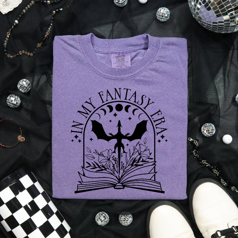 purple tshirt with black design that reads in my fantasy era with a dragon coming out of a book