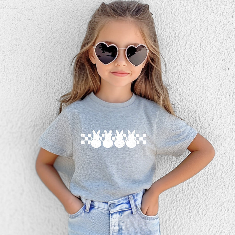 Child wearing a gray t-shirt with a graphic design and heart-shaped sunglasses against a white background