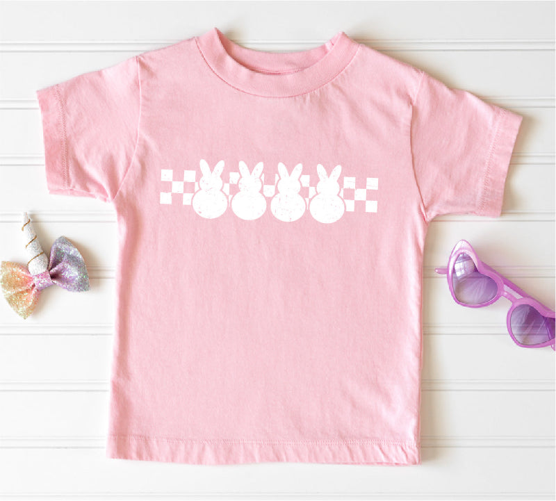 Pink t-shirt with white bunny graphic on a light wooden surface