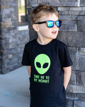 Little boy posing in front of stone wall, black tee with writing saying, "TAKE ME TO MY MOMMY", a lime green alien, font is limegreen - graphic tee