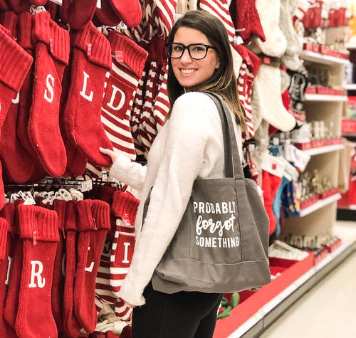 Lady with glasses holding grey large canvas tote thtat says, 
