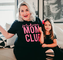 Mom club neon pink on black stacked tee with the writing in neon pink saying, "Mediocre MOM CLUB" with the mom wearing it and the daughter is sitting next to the mom.